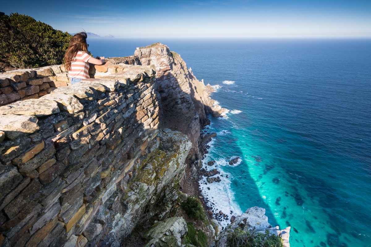 Woman taking photo of cliffs at Cape Point, South Africa