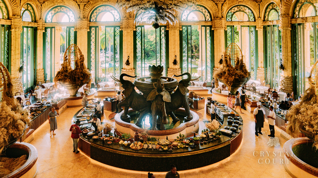 The Crystal Court at The Palace of the Lost City, featuring JAN’s reimagined breakfast buffet with grand elephant fountain centerpiece and opulent interior decor.